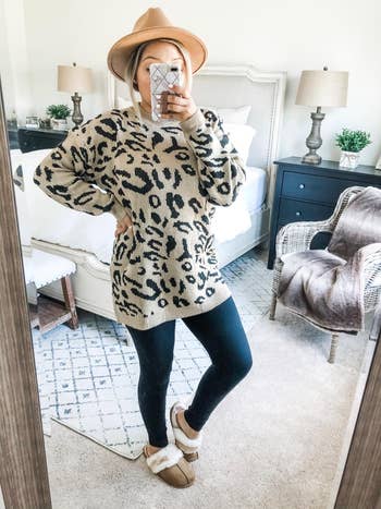 reviewer mirror selfie wearing the leopard print sweater dress with leggings