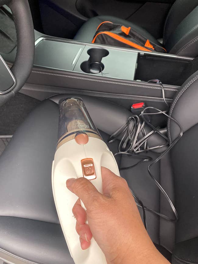 A reviewer holding the vacuum in their car