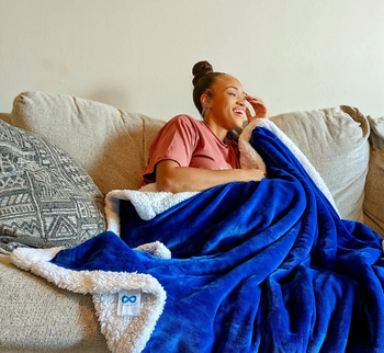 reviewer wrapped up in the blue and white sherpa fleece-lined throw blanket