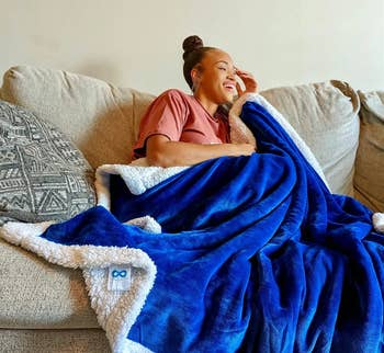 reviewer wrapped up in the blue and white sherpa fleece-lined throw blanket