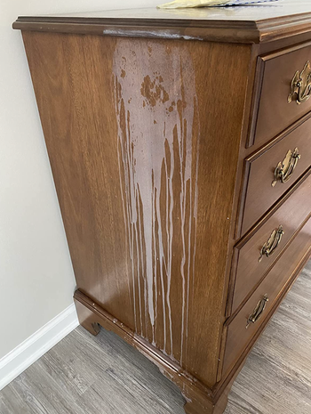 reviewer photo of a wooden dresser with a white watermark stain on it