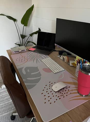 Home office desk with a laptop, monitor, mouse on top a pastel mat with a minimalist print 