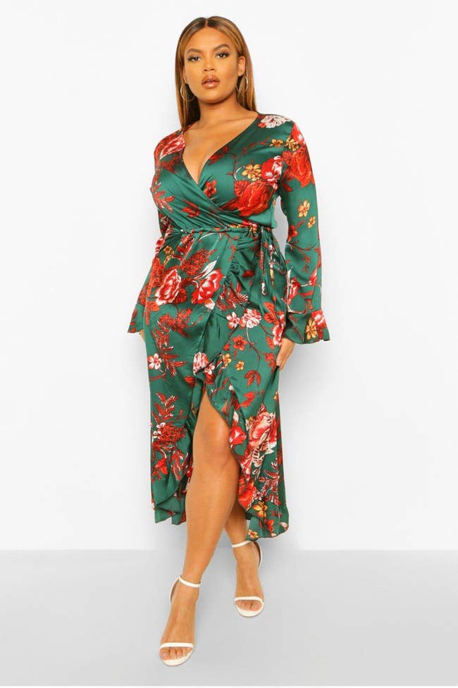 Model in a green silky V-neck long sleeved wrap dress with an asymmetrical hem and red flowers 