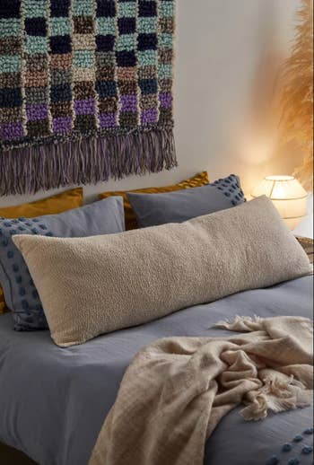 Image of the beige body pillow on a bed