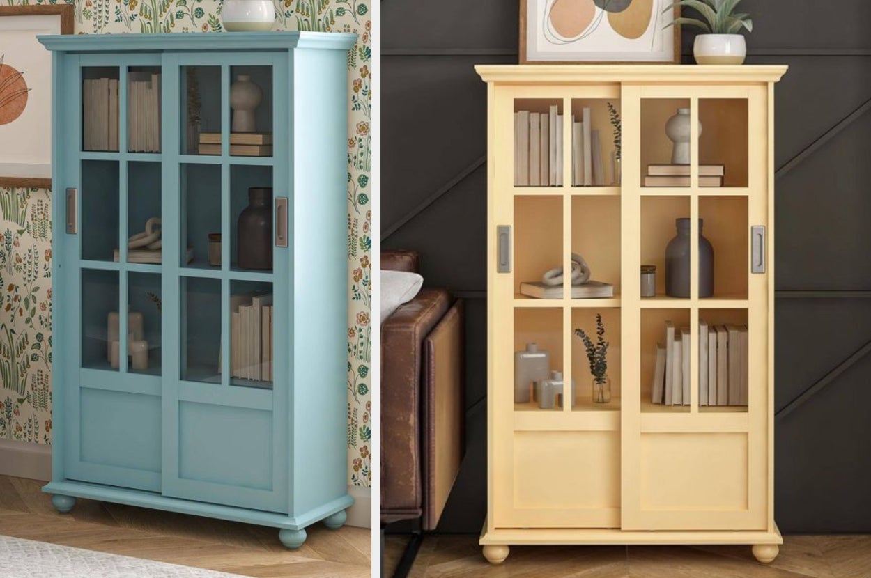 Blue accent cabinet with glass windows and books inside, product in yellow against a black wall