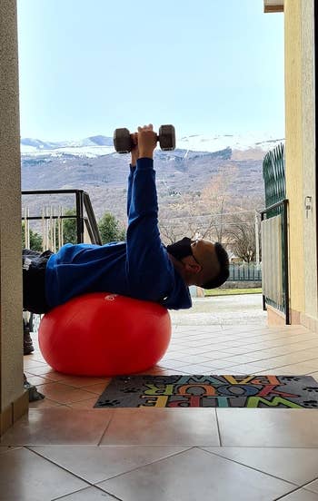 reviewer using the red exercise ball while lifting weights