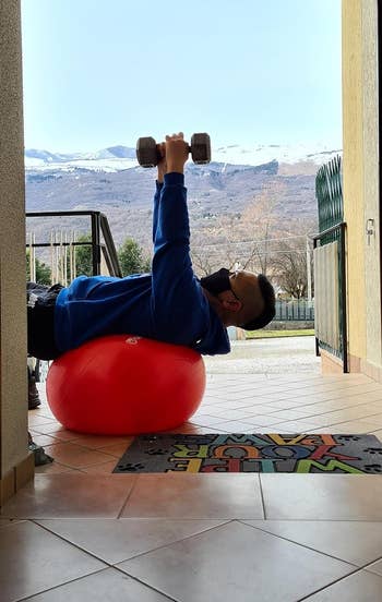 reviewer using the red exercise ball while lifting weights