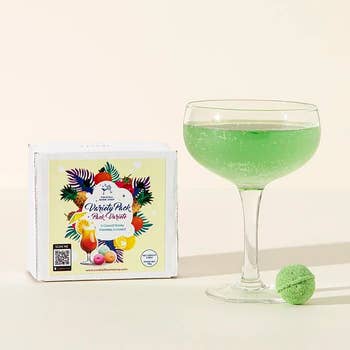A cocktail next to a green drink bomb and the drink bomb box