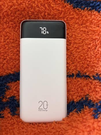 Portable powerfulness  slope  with a integer  show  showing 78% charge, resting connected  textured fabric. Label indicates 20W accelerated  charging capability