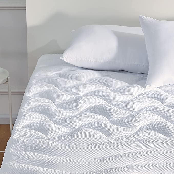 a white quilted mattress topper on a bed with two white pillows on top of it