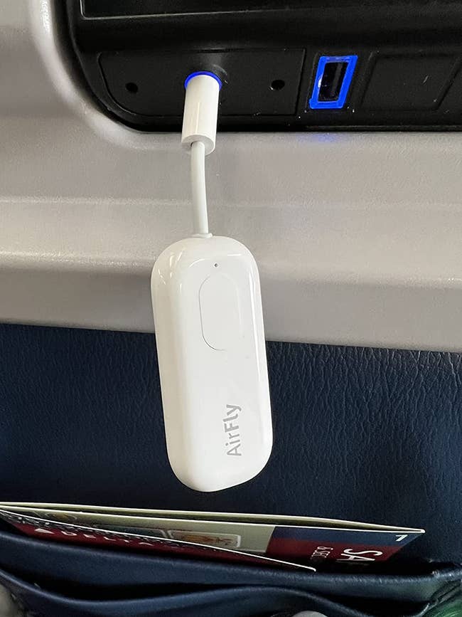 Reviewer's AirFly plugged into the headphone jack on the back of a plane seat