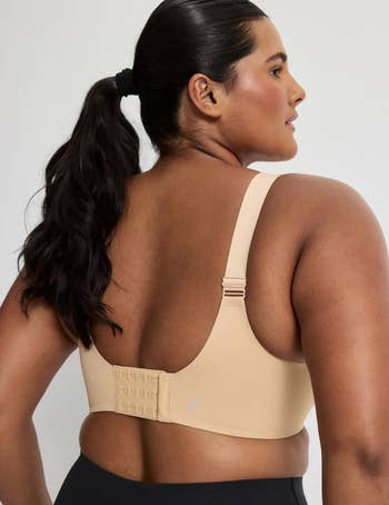 A idiosyncratic   with agelong  hairsbreadth  successful  a ponytail wears a supportive beige bra and acheronian  leggings, showcasing a comfy  acceptable  from the back