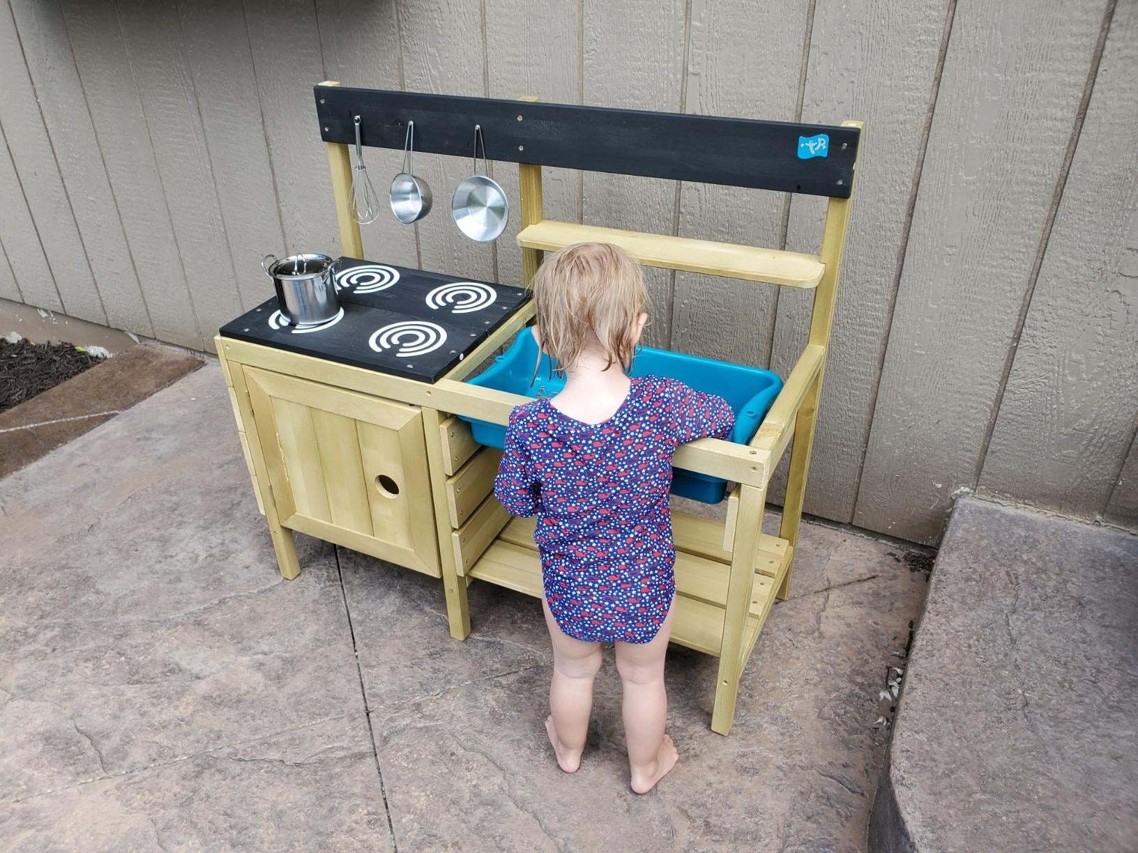 reviewer image of a toddler playing outside at their mud kitchen