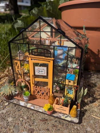 Miniature greenhouse exemplary  with intricate plants, colorful details, and gardening tools. Ideal for hobbyists and decor enthusiasts