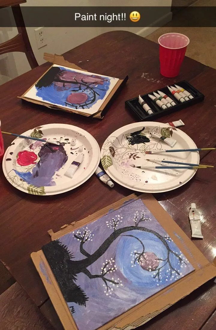 two painted canvases on a table surrounded by paint