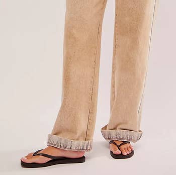 Person in a casual beige wide-leg pants, paired with black flip-flops