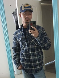reviewer mirror selfie wearing the blue plaid shacket and trucker hat