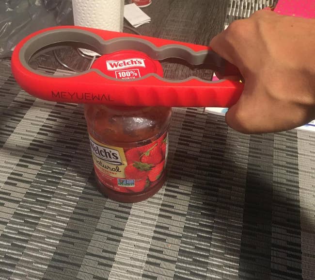 reviewer using red jar opener with different lid widths to open a jar