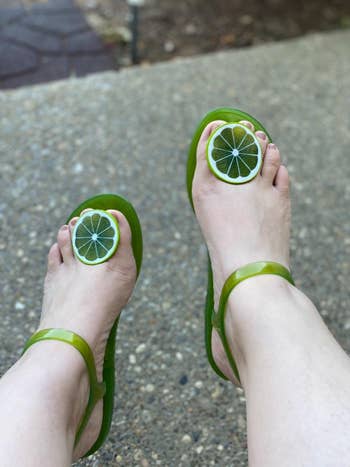 reviewer wearing the flats in green with a lime between the big and second toe