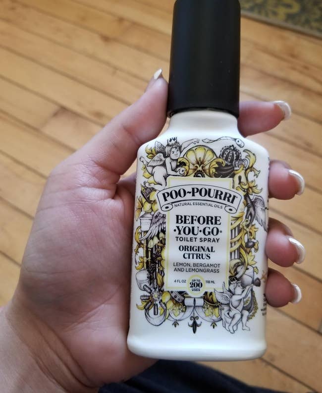 reviewer holding the citrus scented poo-pourri
