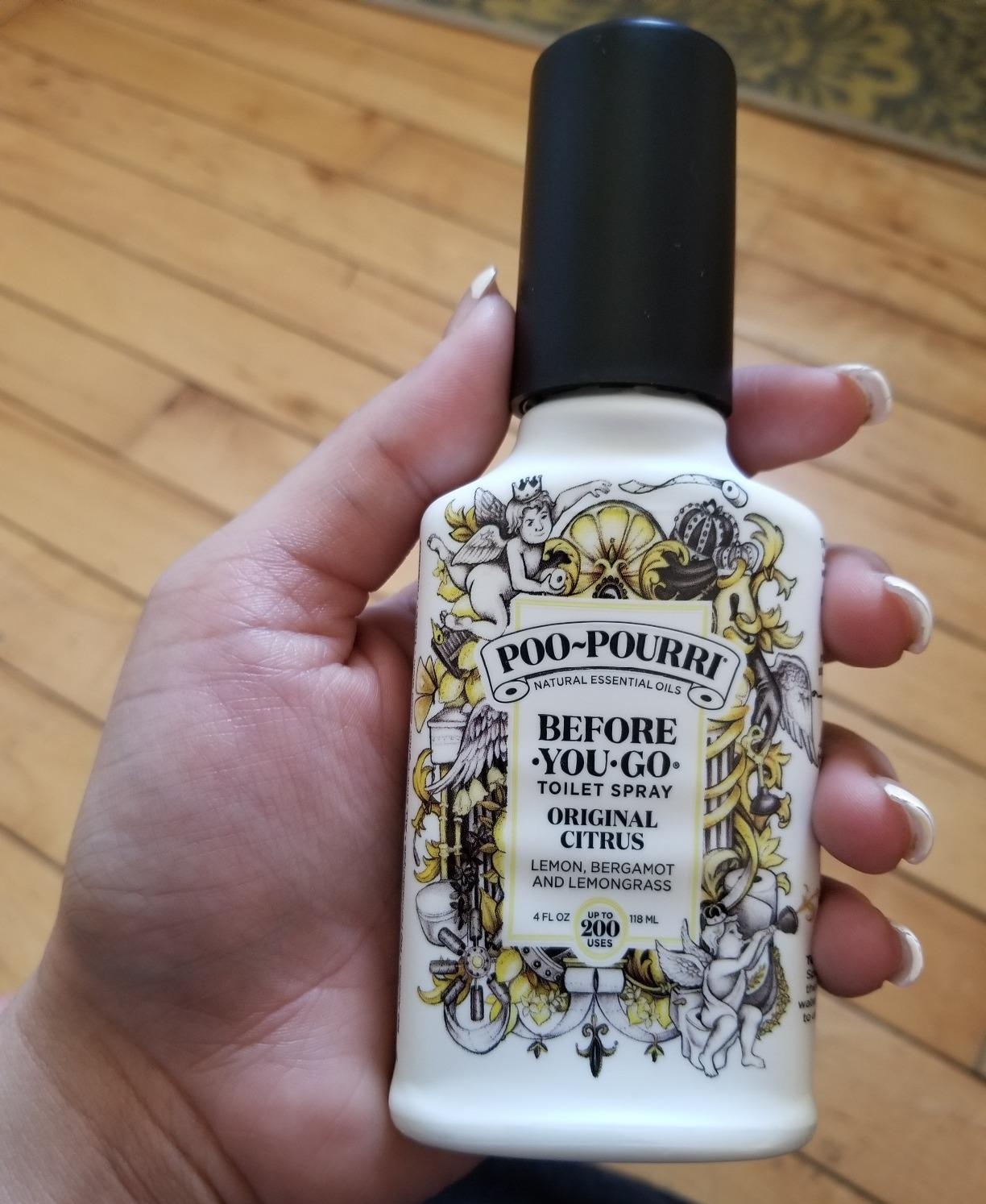 reviewer holding the citrus scented poo-pourri
