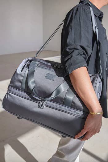 model carrying gray duffel bag