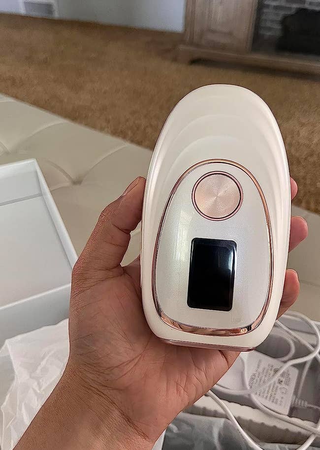 a reviewer holding the laser hair removal device 