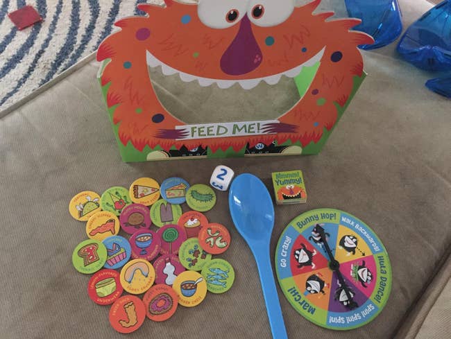Feed the Woozle game with game pieces, tokens, spinner, and blue spoon displayed on a table
