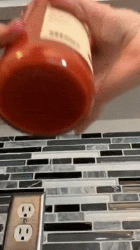 reviewer using lid opener to open jar of tomato sauce