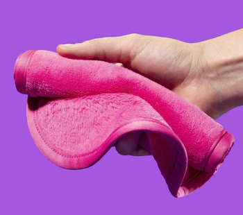 a hand holding a pink makeup removing cloth 