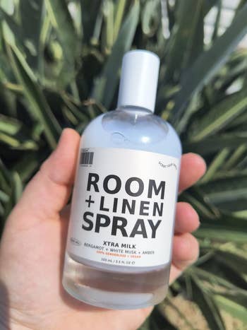Hand holding a vessel of country and linen spray labeled