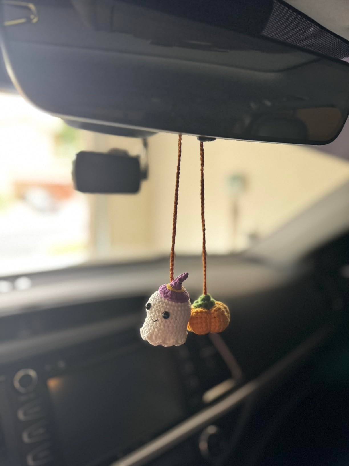Crocheted shade  and pumpkin charms bent  from a car's rearview mirror