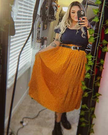 Reviewer wearing pleated skirt in mustard yellow