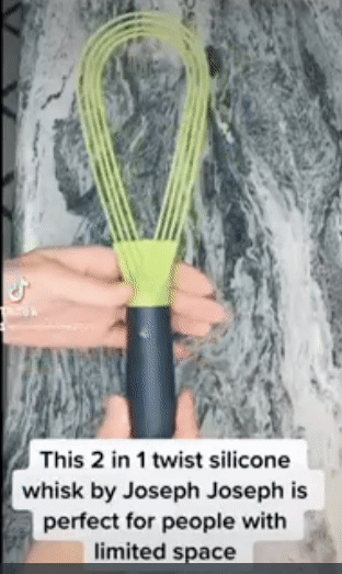 A person twisting a green flat whisk to turn into a balloon whisk 