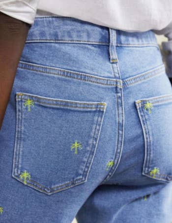 close up on back of jeans with two large pockets and more embroidery