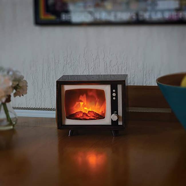 tiny tv with fireplace on screen sitting on a shelf 