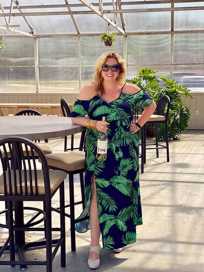 Reviewer is wearing the black maxi dress with large green palm prints throughout