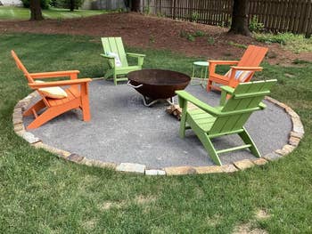 Four Adirondack chairs encircle a fire pit on a stone patio in a grassy backyard