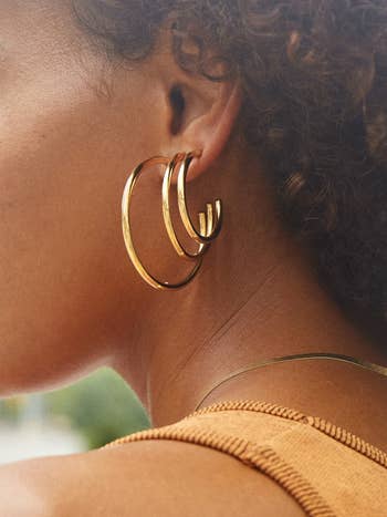 model wearing gold hoops in small, medium, and large