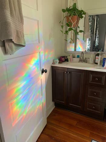 reviewer photo of reflected rainbows on their bathroom door and wall