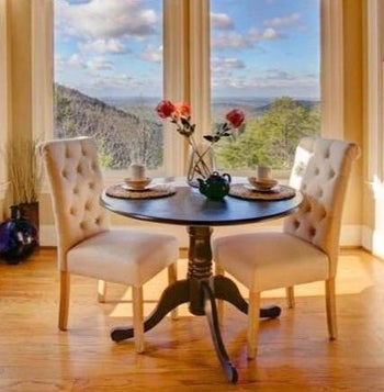 reviewer photo of two of the white chairs at a small round dining table