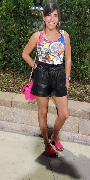 reviewer wearing the black faux leather shorts with a tank and sandals