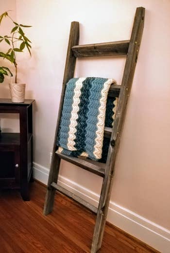 Reviewer image of the brown ladder shelf with a quilt