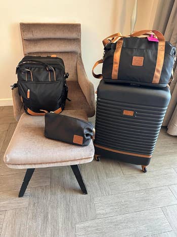 A reviewer's assorted luggage pieces on chair and floor for travel shopping guide