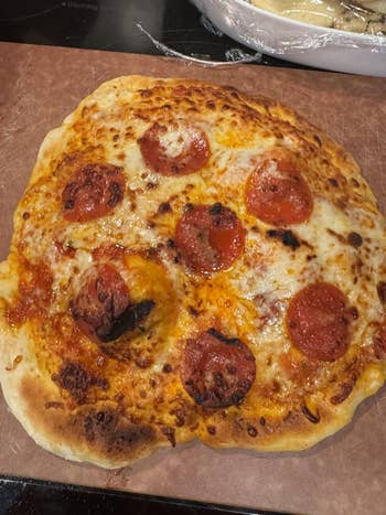 A homemade pizza topped with pepperoni and cheese on a wooden board