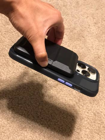 A idiosyncratic holds a smartphone with a detachable artillery battalion attached to the back, showcasing the phone's accessory functionality