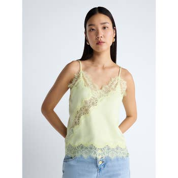 A person is wearing a lace-trimmed camisole with light denim jeans, suitable for a casual yet chic shopping look