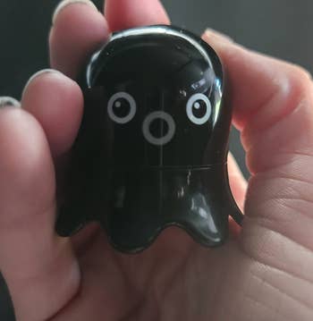 A black small octopus shaped remover in a reviewer's hand 