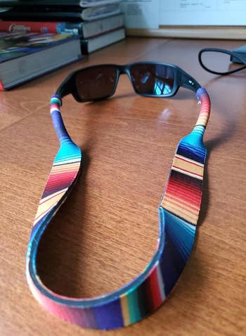 sunglasses with a rainbow striped strap attached tot them 