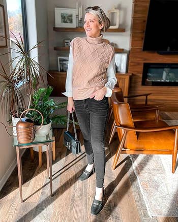 A model wearing a knitted vest, white blouse, black jeans, and mary jane shoes